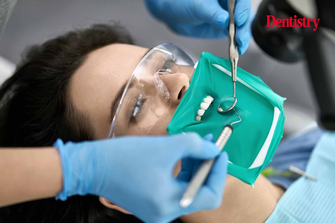 Patient receiving root canal treatment with a green rubber dam isolating the tooth